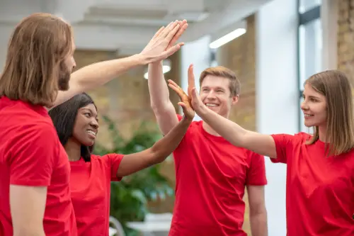 4 karyawan sedang melakukan kegiatan team building menggunakan baju merah yang seragam